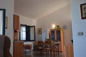 A compact kitchen with a dining area, wooden cabinets, and a clock on the wall. - Fagr-gai014p in Agrustos (Budoni)
