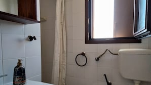 Ein Badezimmer mit einem weißen Waschbecken, einem Bidet und einem Fenster mit Blick ins Freie.