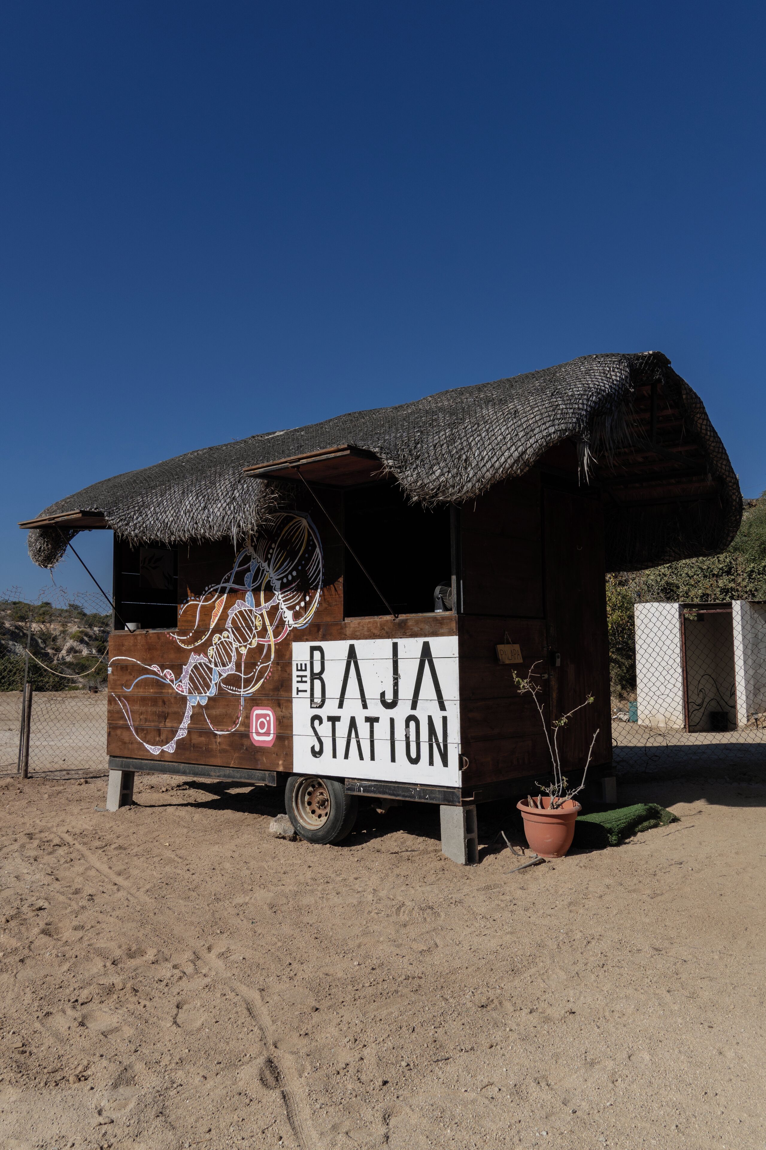 A small wooden structure with a thatched roof labeled "The Baja Station."