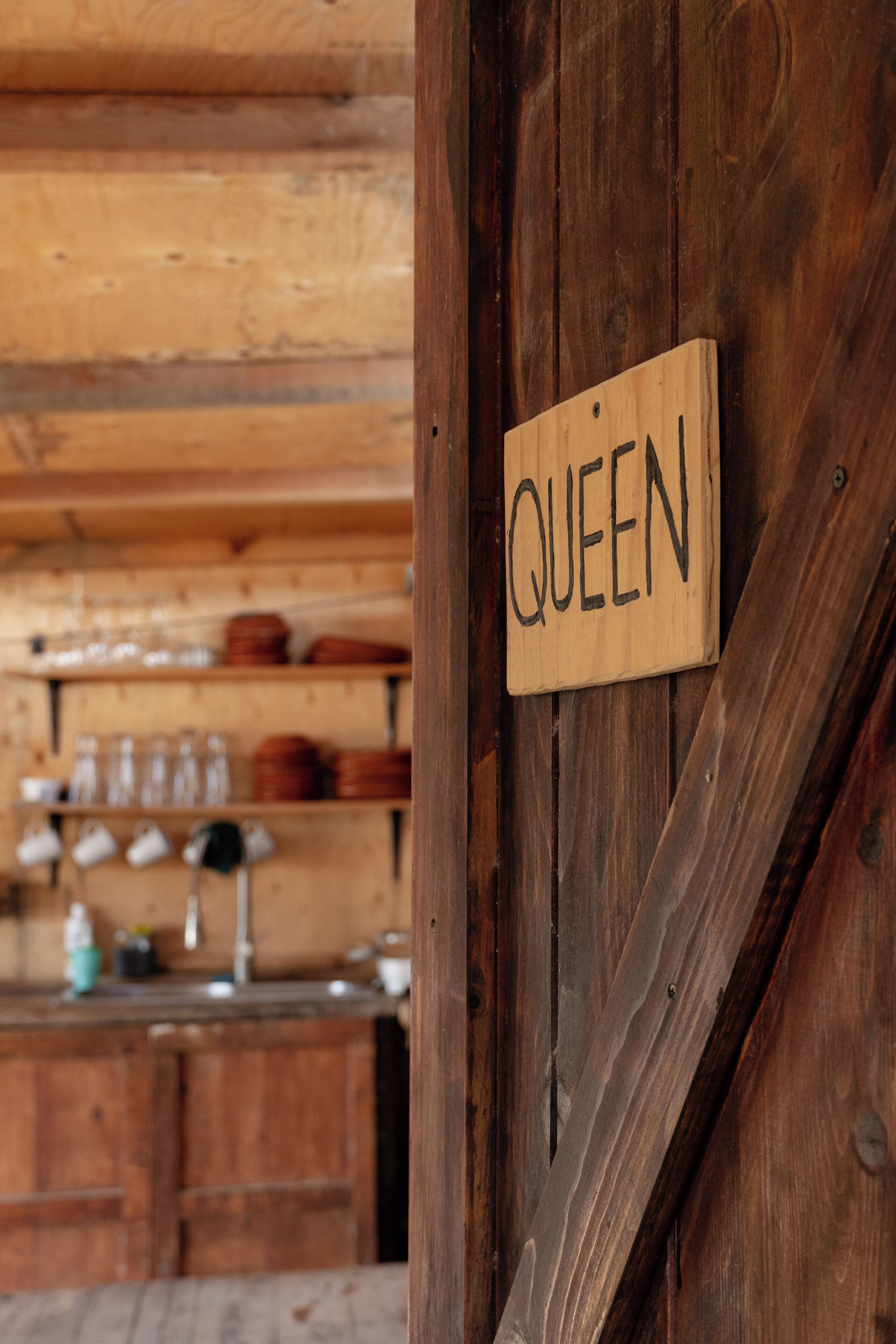 Una puerta de madera con un letrero que dice "QUEEN".