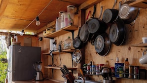 Una cocina rústica con armarios de madera, estufa y ollas colgantes.