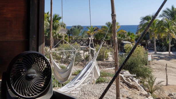 Una habitación con vista al océano, una hamaca y un ventilador.