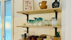 Cozinha com micro-ondas, máquina de café e diversos copos e taças nas prateleiras.