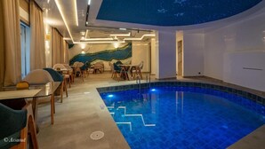 Ein moderner, überdachter Pool mit Sternenhimmel, umgeben von einem Essbereich mit Tischen und Stühlen.