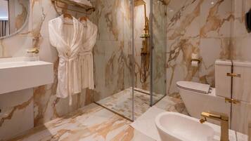 A bathroom with marble walls, a glass shower enclosure, a white bathtub, and a toilet.