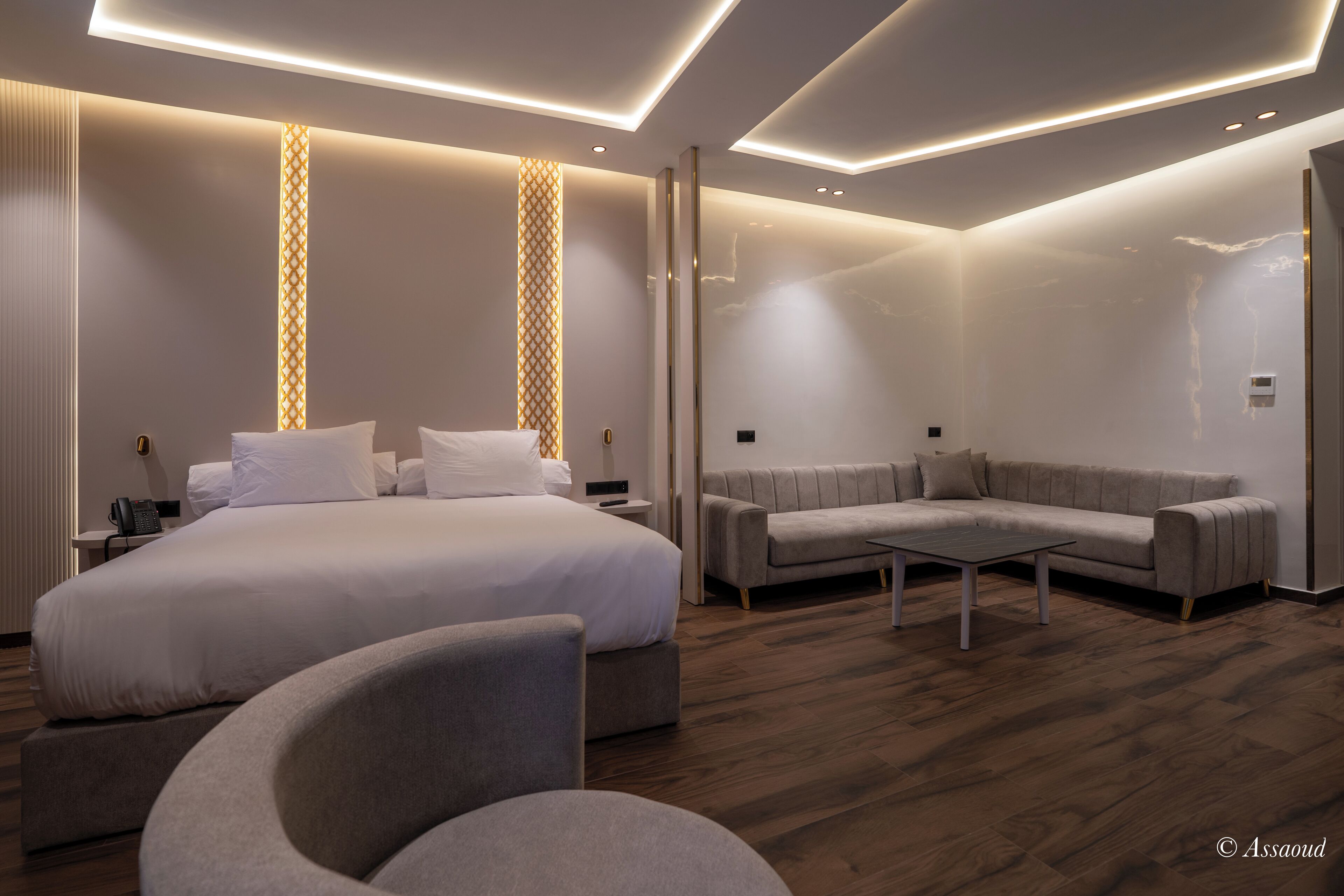 A modern hotel room with a large bed, a sofa, and a coffee table.