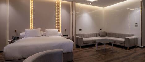 A modern hotel room with a large bed, a sofa, and a coffee table.