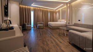 Ein modernes Hotelzimmer mit einer Couch, einem Bett, einem Couchtisch und einem Fernseher.