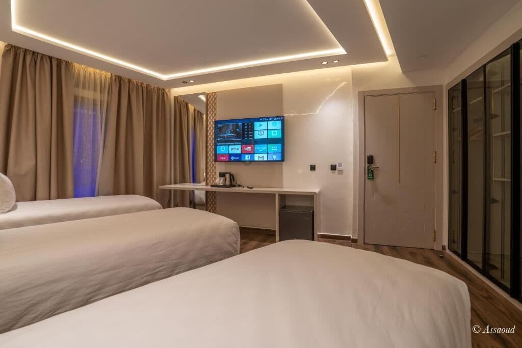 Una habitación de hotel con dos camas, un escritorio y un televisor de pantalla plana, además de una puerta corredera.
