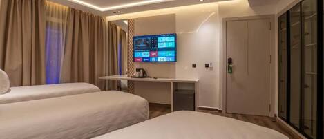 Una habitación de hotel con dos camas, un escritorio y un televisor de pantalla plana, además de una puerta corredera.