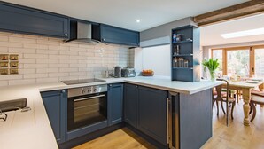Uma cozinha moderna com armários azul escuro, bancada branca e forno embutido.