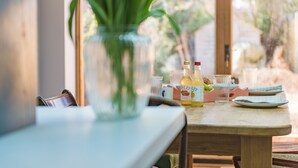 Uma mesa de madeira com um vaso de vidro, garrafas e copos, sugerindo um ambiente de refeições.