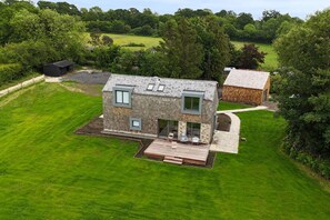 A modern two-story house with a deck, surrounded by lush greenery and a well-maintained lawn. - Brook  Lodge Farm -  a holiday let that sleeps 6 guests  in 3 bedrooms (Uckfield)