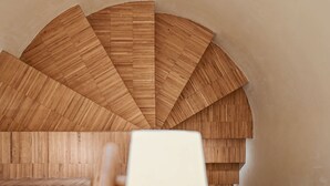 Un escalier en colimaçon en bois, dont le motif évoque un éventail, menant à un niveau supérieur.