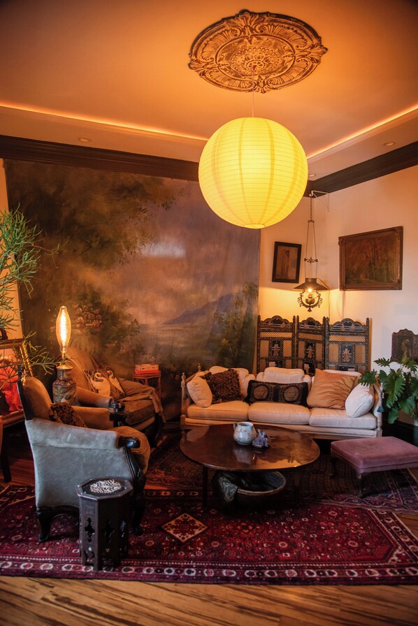 A cozy living room with a sofa, armchairs, a coffee table, and a hanging paper lantern. - Miss Scarlet 3-bedroom cottage in Historic downtown Hot Springs (Hot Springs)