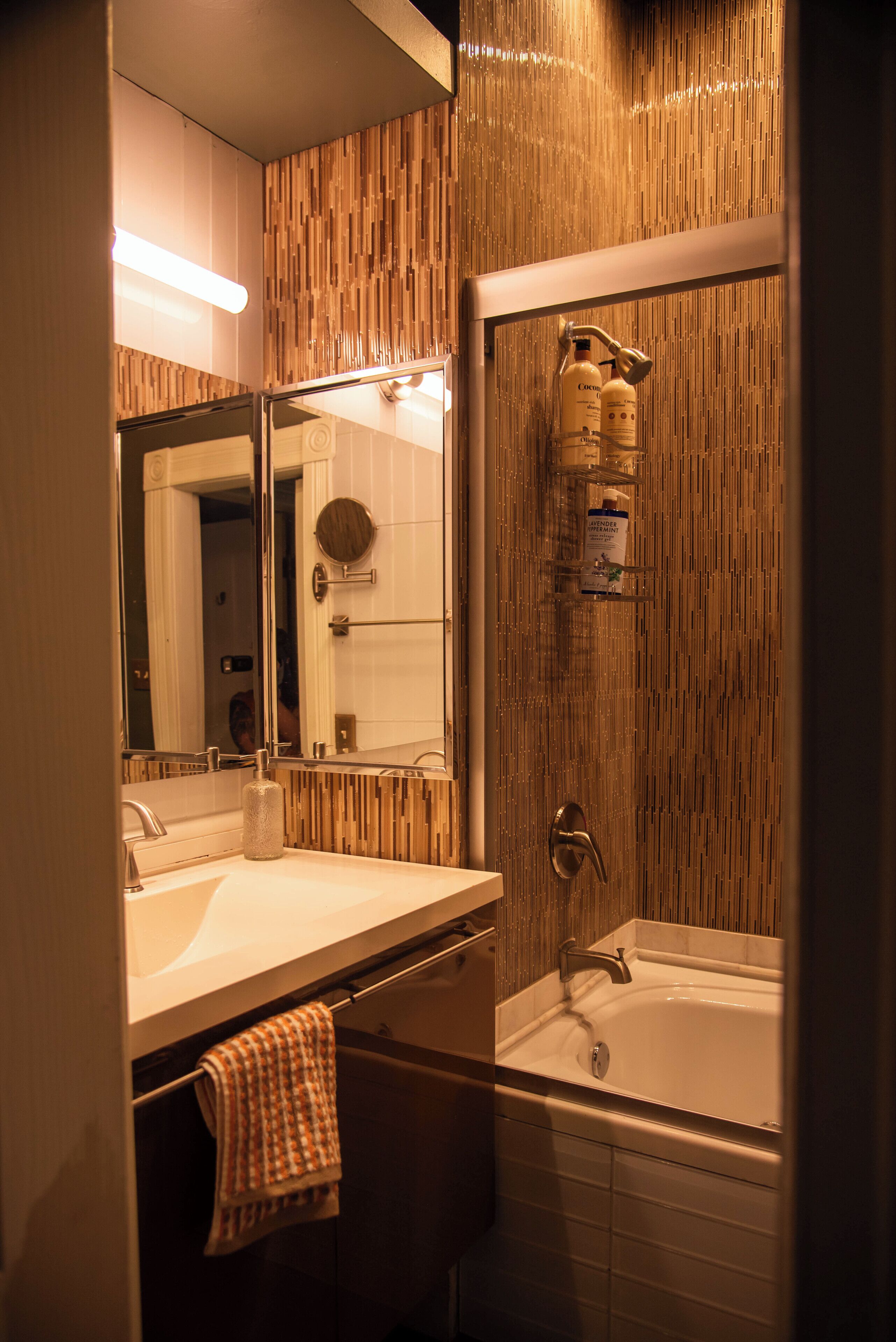 Un baño con pared de madera, un lavabo, un espejo y una bañera.