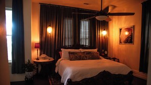 A bedroom with a large bed, a ceiling fan, a nightstand, and a potted plant. - Miss Scarlet 3-bedroom cottage in Historic downtown Hot Springs (Hot Springs)