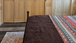 A bedroom with wooden walls, a ceiling fan, and a bed with a patterned bedspread. - Wonderful 1-bedroom cabin with AC in charming Potsdam on a brook. (Potsdam)