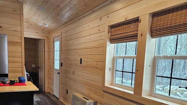 A cabin interior with wooden walls, a kitchenette, and large windows with blinds. - Wonderful 1-bedroom cabin with AC in charming Potsdam on a brook. (Potsdam)