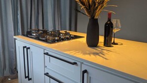 A modern kitchen with a gas stove, a vase of dried flowers, and a wine bottle. - Modern Cottage with Pool  in Cedar Valley (Cedar Valley)