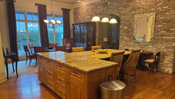 A kitchen with a large island, wooden cabinets, and a brick wall. - Family Holiday Rental (Baton Rouge)