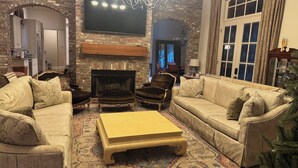 A cozy living room with a fireplace, a television, and a chandelier. - Family Holiday Rental (Baton Rouge)
