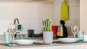A dining table set with plates, glasses, and a small potted cactus. - Apartment in Metro U. de Chile with Balcony, Gym & Swimming Pool, Historic Center Santiago (Santiago)