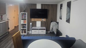 A living room with a flat-screen TV, a bookshelf, a white cabinet, and a blue sofa. - River View Flat, 5 minutes Drive to Bluewater and Greenhithe Station (Greenhithe)