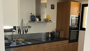 A modern kitchen with wooden cabinets, a black countertop, and a stainless steel sink. - Small, quiet house (Ollioules)