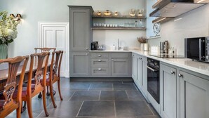Una cocina moderna con armarios grises, un comedor con sillas de madera y un horno empotrado.