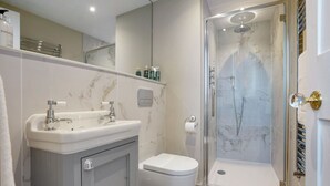 Un baño moderno con lavamanos, inodoro y ducha con cerramiento de vidrio de mármol.