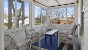 A covered porch with wicker furniture and a view of the neighborhood. - The Coastal Connection (South Portland)