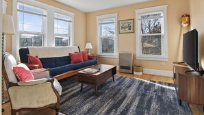 A living room with a sofa, armchair, coffee table, and a television. - The Coastal Connection (South Portland)