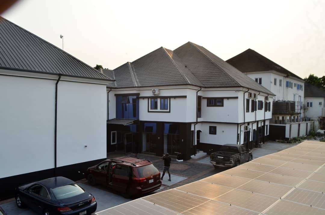 A residential area with houses, parked cars, and a solar panel array.