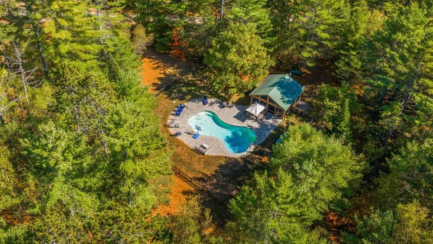 Vista aérea de un resort apartado con piscina, zona de descanso y una cabaña pequeña.