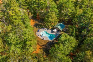 Luchtbeeld van een afgelegen resort met een zwembad, een loungegedeelte en een klein huisje.