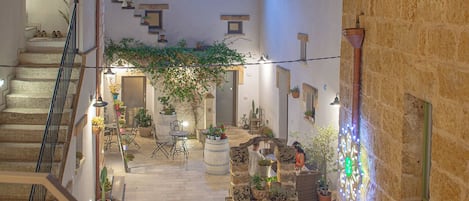 A courtyard with a staircase, potted plants, and a stone wall.
