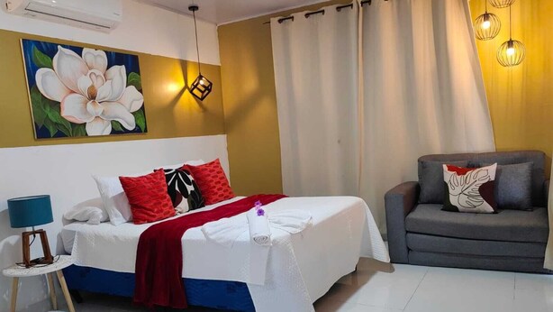 Une chambre à coucher avec un lit, une chaise, une lampe et un tableau au mur.