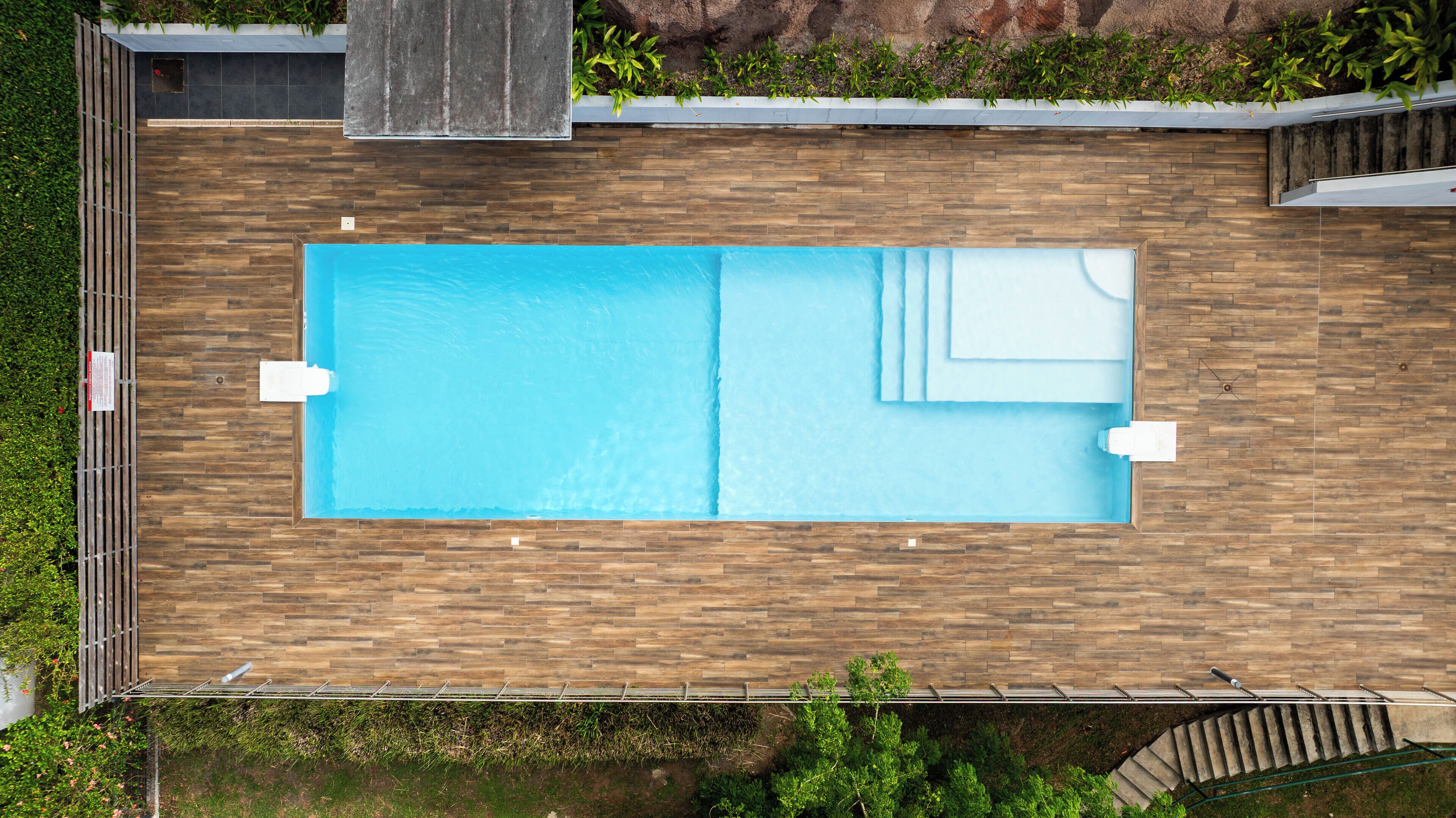 Une piscine rectangulaire entourée d’une terrasse en bois.