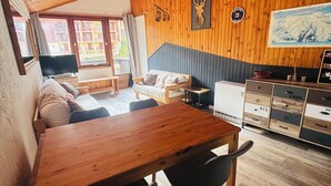 Une pièce chaleureuse avec un plafond en bois, une table à manger avec des chaises, un canapé et un téléviseur.