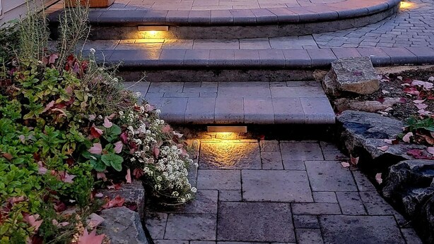 Ein Terrassenbereich mit Holzboden, Gartenmöbeln und Lichterketten.
