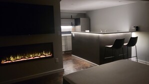 Ein modernes Hotelzimmer mit Kamin, einer kleinen Küchenzeile und einer Sitzecke mit zwei Sesseln.