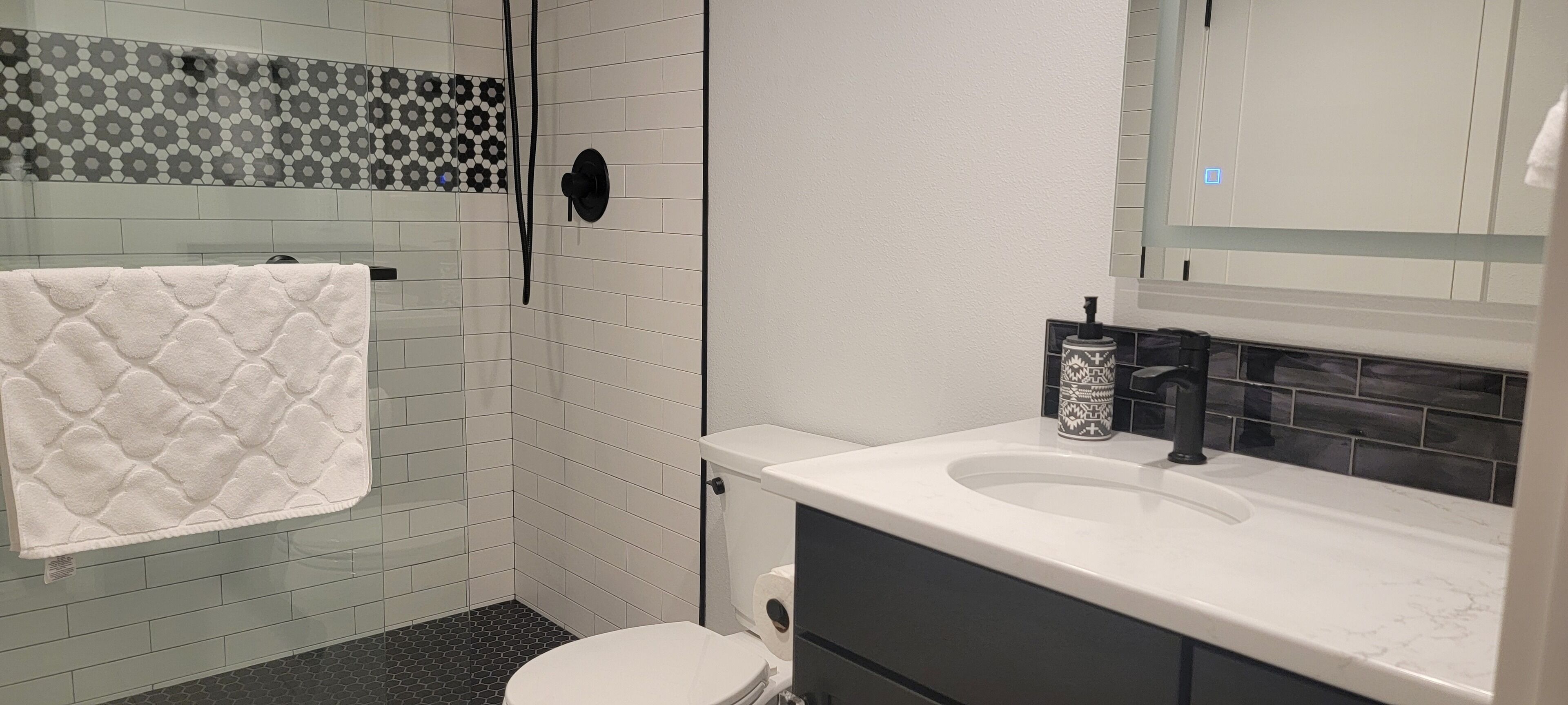 A bathroom with a white toilet, a shower with a glass door, and a sink with a black faucet.