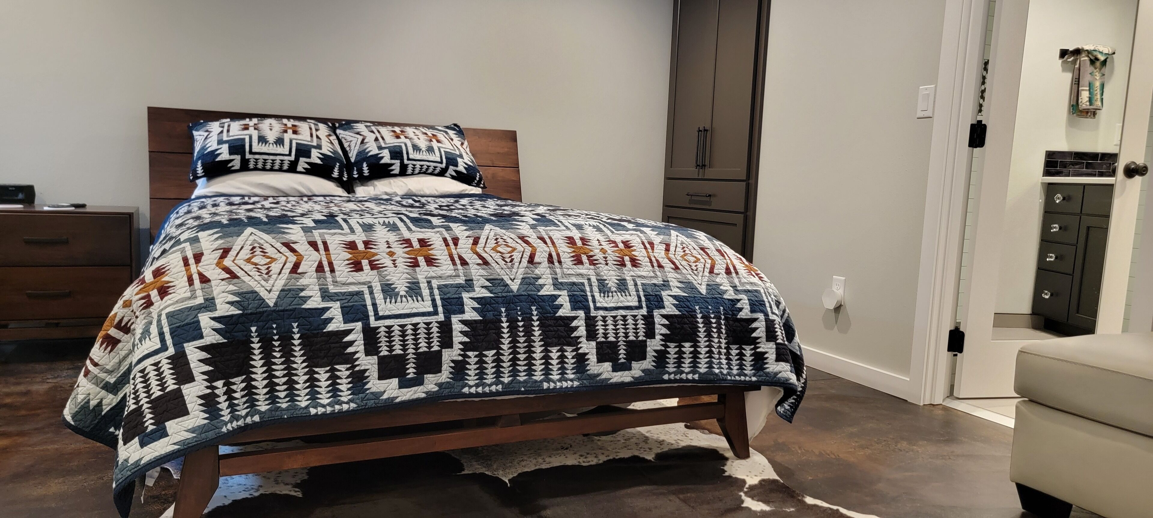 Ein Schlafzimmer mit einem Bett, einem Holzkopfstück, einem Nachttisch, einer Kommode und einem Kleiderschrank.
