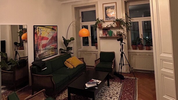 Ein Wohnzimmer mit einer Couch, Sesseln, einem Couchtisch, einer Stehlampe und einem Bild an der Wand.