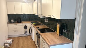 Eine moderne Küche mit weißen Schränken, einer Holzauskładung, einem Einbauofen und einer schwarzen Spritzschutzwand.