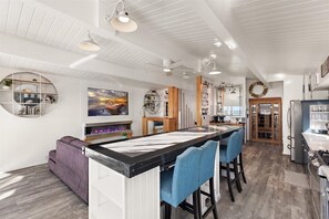 Una cocina moderna con una isla central, iluminación colgante y vistas al comedor.