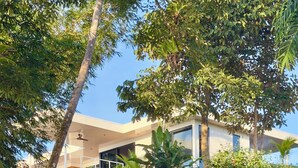 A modern house with a flat roof, large windows, and a surrounding lush garden. - Escape to your oceanfront retreat: Sea La Vie! (Playa Hermosa Boca Chica)