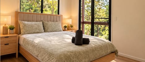 A bedroom with a bed, nightstands, a ceiling fan, and large windows.