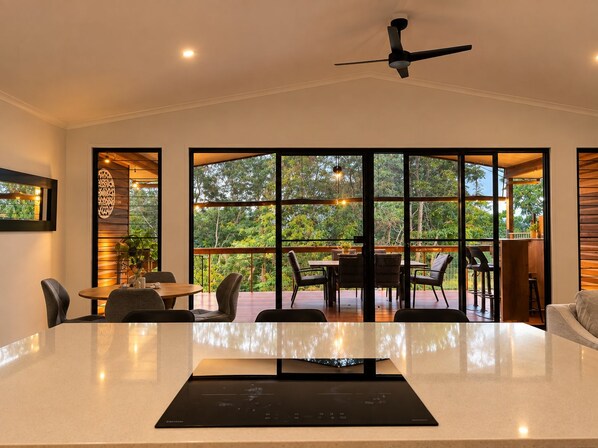 A modern dining area with a large table, chairs, and a ceiling fan.